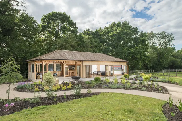 Large bespoke Crown timber building with an al fresco room, set among planted borders