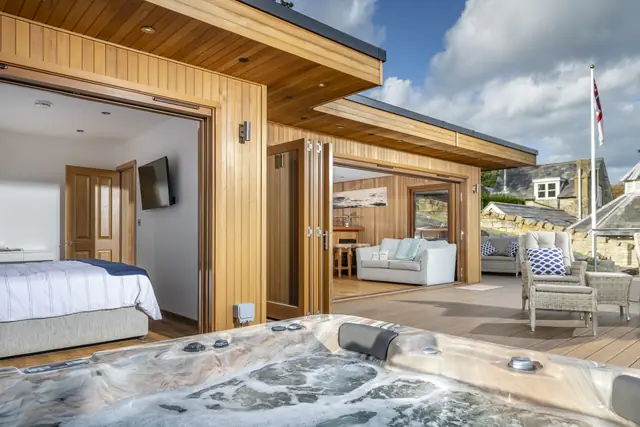 Crown timber building with a bedroom and living room opening onto a terrace and hot tub