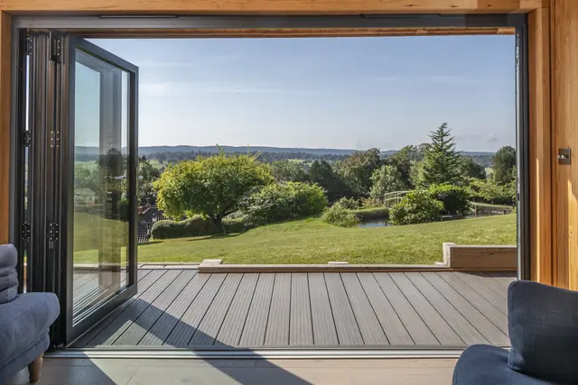View across a garden from inside a Crown building through open dark grey doors